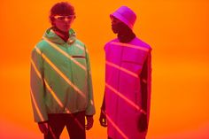 two young men standing next to each other in front of an orange and pink background