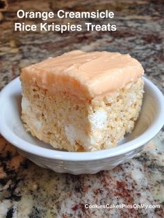 a piece of orange creamsice rice krispies treats in a white bowl on a marble counter