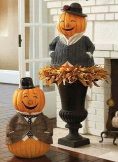 two pumpkins are sitting on top of each other in front of a fire place