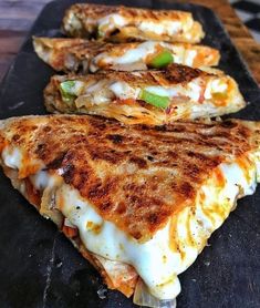 three quesadillas are lined up on a black plate