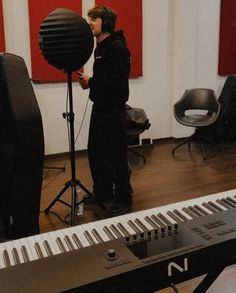 a person standing in front of a piano and microphone with a large black object behind them