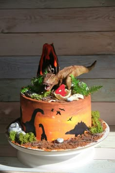 a cake decorated with dinosaurs and plants on a table