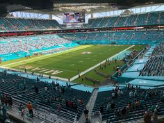 a stadium filled with lots of people standing on top of a green field covered in blue seats