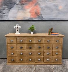 a wooden dresser with many drawers in front of a painting