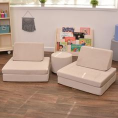 two white chairs sitting on top of a hard wood floor next to a book shelf