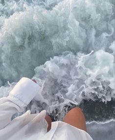 a person laying on the beach with their feet in the water and foamy waves behind them