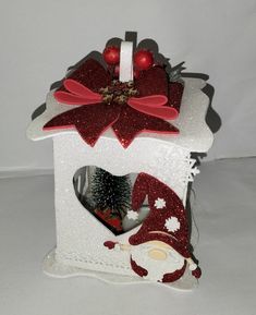 a white birdhouse decorated with red and silver decorations