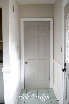 an empty hallway with a white door and tile floor in front of the entrance way