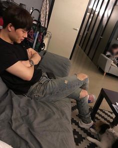 a young man sitting on top of a bed next to a black and white dog