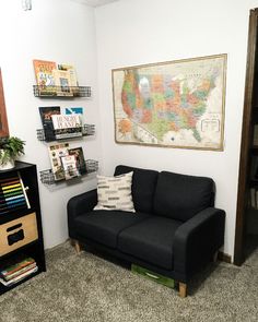 a living room with a couch, book shelf and map on the wall above it