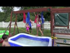 three children playing in an inflatable pool on a backyard swing set with two adults and one child