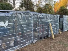 the fence is covered with plastic sheeting and chicken cages are lined up on top of each other