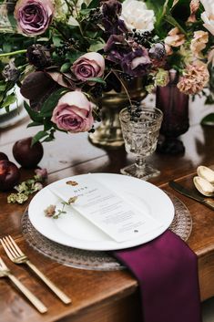 the table is set with purple and white flowers, silverware, and napkins