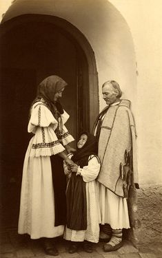 an old black and white photo of two women standing in front of a door with a child