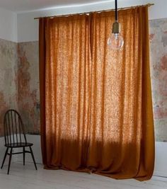 an orange curtain is hanging in front of a chair