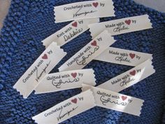 several name tags with hearts on them sitting on top of a blue knitted blanket