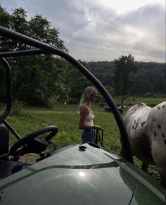 a woman standing next to a horse on top of a lush green field