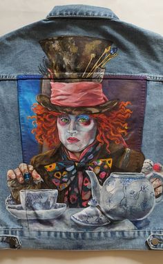 a jean jacket with a painting of a clown holding a teapot on it's lap