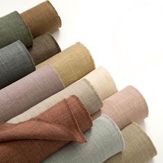 various colors of linens laid out on a white surface with one rolled up in the middle