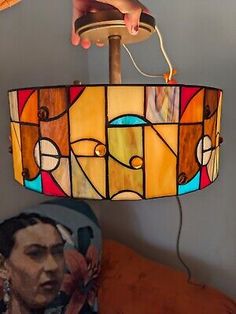 a lamp with a woman's face on it and a hand holding the light