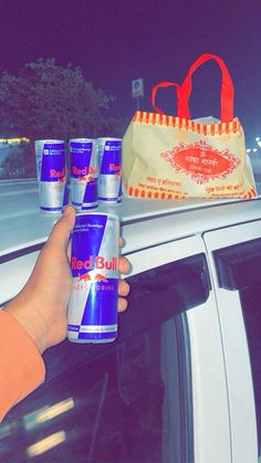 a person is holding six bottles of beer in front of a car window at night