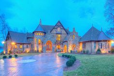 a large stone house with lots of windows and lights on it's front entrance