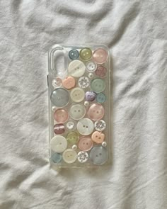 an iphone case with buttons in it laying on a white sheet covered tablecloth,