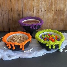 three crocheted bowls with candy and candies in them sitting on a table