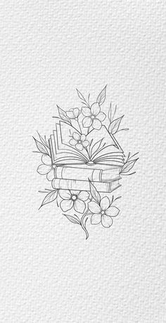 an open book with flowers and leaves on it, sitting next to a pile of books