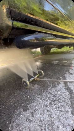 a sprinkler is spraying water onto the ground next to a parked car