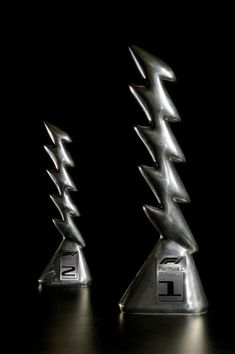 two silver trophies with lightning bolts on them in the middle of a dark room,