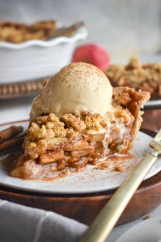 a slice of apple crisp pie on a plate with ice cream and cinnamon sticks next to it