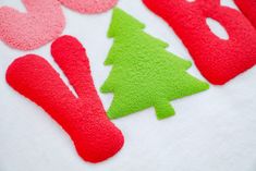 felt christmas trees and hearts on a white tablecloth with the word love spelled out