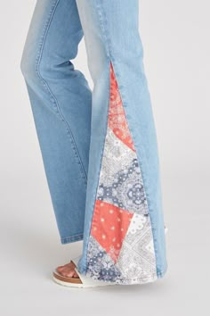 a woman's legs wearing blue jeans with an orange and white patchwork design