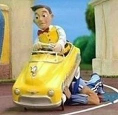 a cartoon character laying on the ground next to a yellow car with a man sitting in it