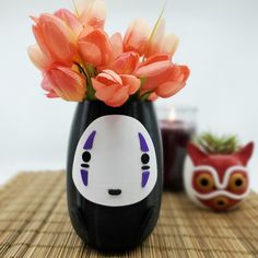 a vase with flowers in it sitting on a bamboo mat next to an owl figurine