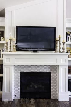 a flat screen tv mounted on top of a white mantle in front of a fireplace