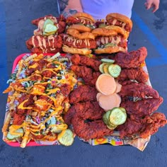 a person standing in front of a table full of fried food and other foods on it