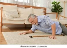 an older man laying on the floor in front of a couch