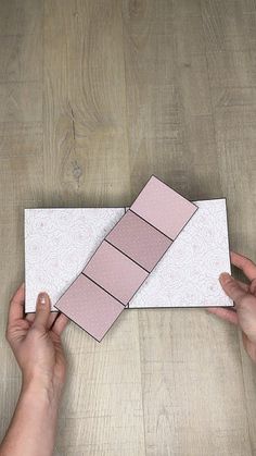 two hands holding a piece of paper on top of a wooden table