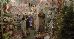 there is a woman standing in the middle of a room full of flowers and garlands