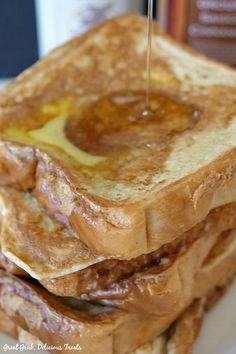 a stack of french toast with syrup being poured on top, sitting on a plate