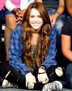 a woman sitting on the ground with her legs crossed in front of her and people behind her