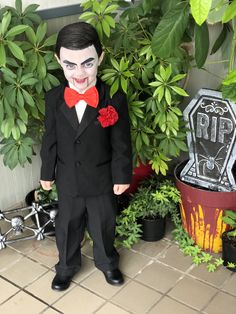 a young boy dressed up as the joker in front of some plants and potted plants