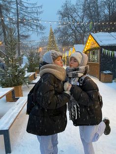 two women are standing in the snow with their arms around each other