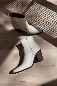 Elevate your footwear collection with the Jackson White Ankle Boots. Featuring pristine white uppers, these boots exude modern sophistication and versatility. The brown block heels provide a stylish contrast and ensure all-day comfort and stability. With convenient inner zippers, slipping them on and off is a breeze, while the outer strap details add a touch of edgy flair. The pointed toes enhance the sleek design, making these boots perfect for any occasion. The Jackson White Ankle Boots seamle White Mid-calf Boots With Stacked Heel For Fall, Modern White High Ankle Heeled Boots, Modern White Ankle Heeled Boots, White Leather Heeled Boots With Zipper, White Ankle Heeled Boots With Zipper, White Ankle Heeled Boots With Zipper Closure, White Zipper Closure Ankle Heeled Boots, Modern White Ankle-high Heeled Boots, Modern White Square Toe Boots