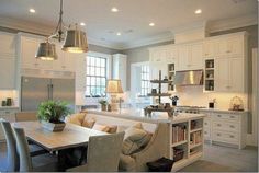 a kitchen filled with lots of white cabinets and counter top next to a dining room table