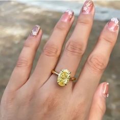 a close up of a person's hand with a yellow diamond ring on it