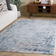 a living room area with a couch, coffee table and rug on the hardwood floor