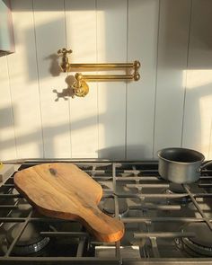 a wooden cutting board sitting on top of an oven burner next to a frying pan